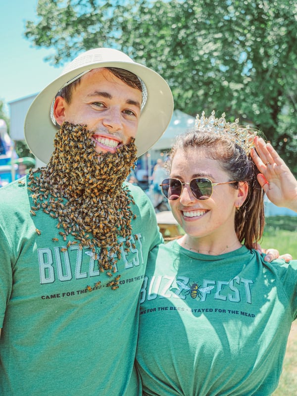 A man wearing a beard of bees and a woman wearing sunglasses