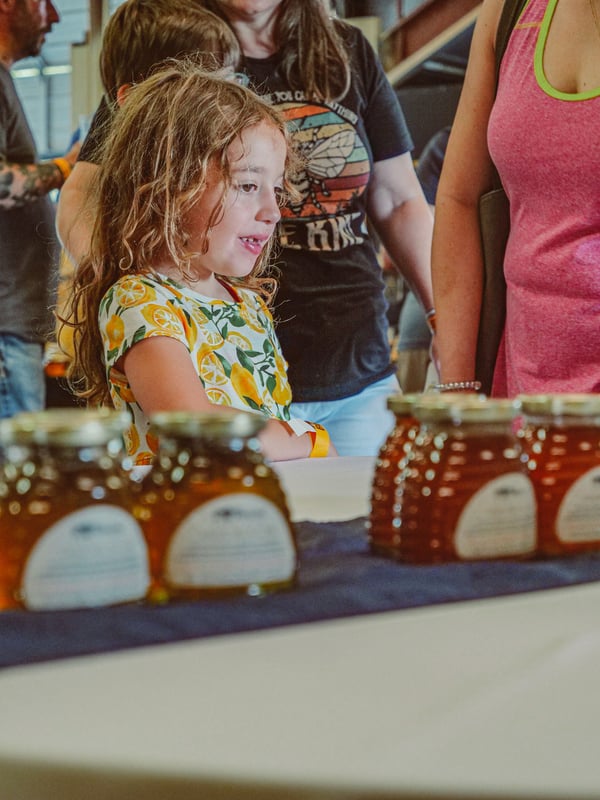 A child looking at bottles of honey