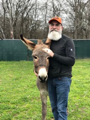 Man with beard standing with donkey