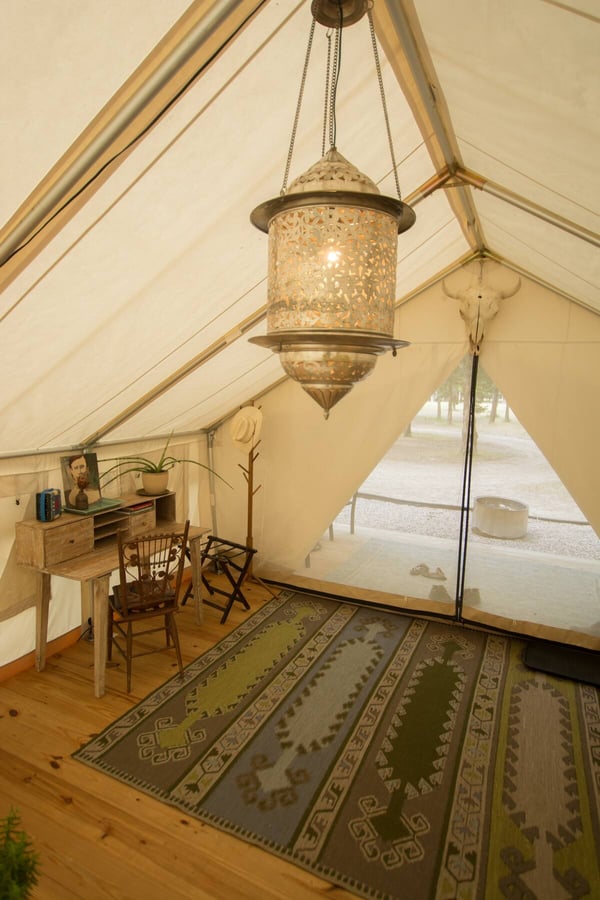 Tent interior showing zippered door, rug, and lamp
