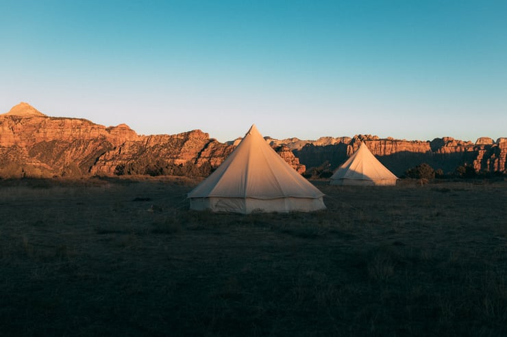 glamping tents at sunset with mountains in background