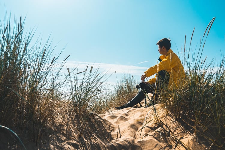 man sitting on dune near beach